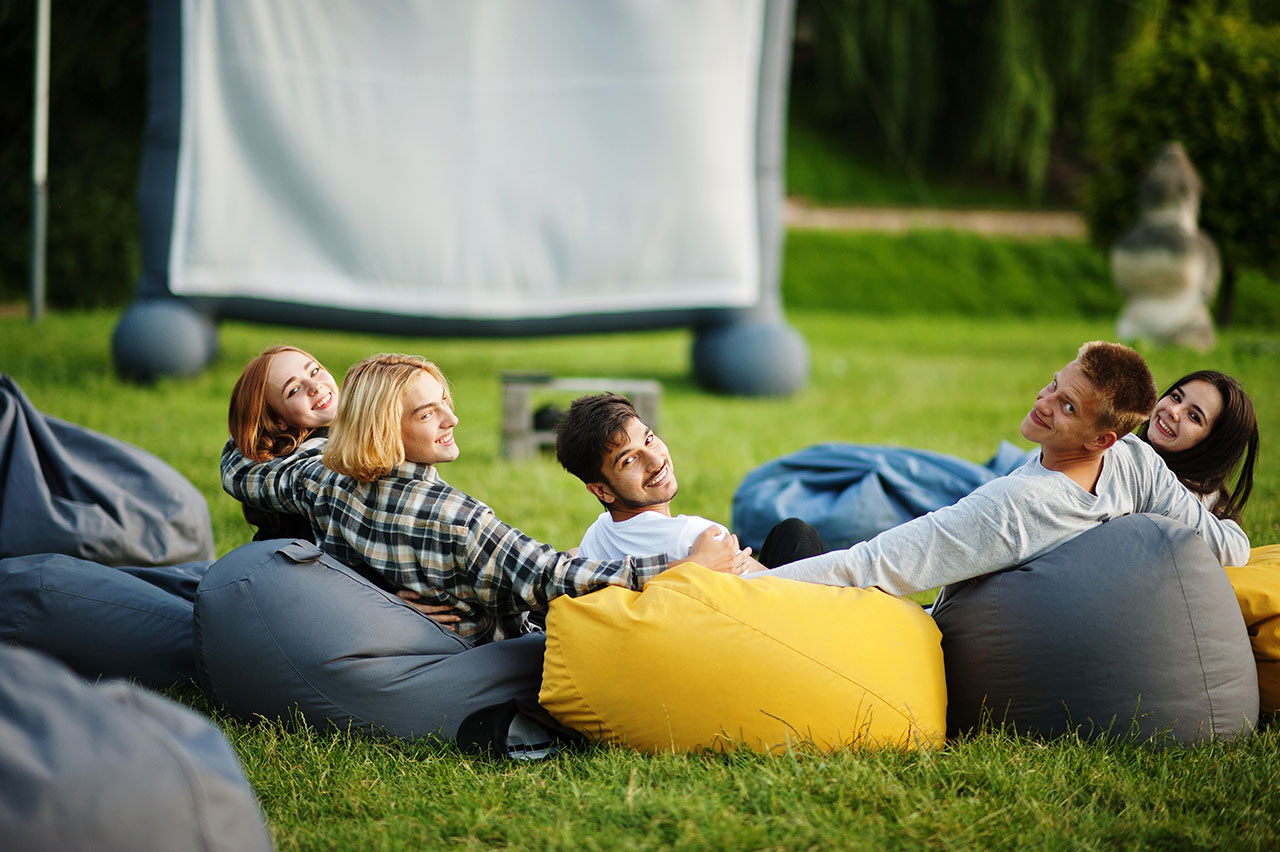 Young multi ethnic group of people watching movie at poof in ope